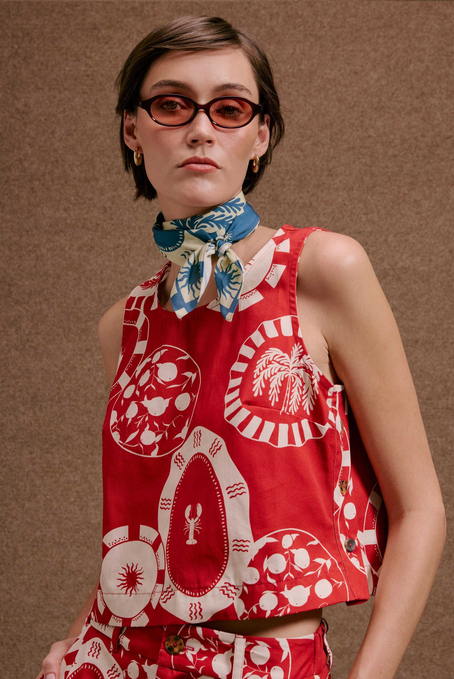 Regata Toscana Pratinhos Vermelho, vibrante estampa de pratinhos brancos com coqueiros e lagosta. Look de verão chic.