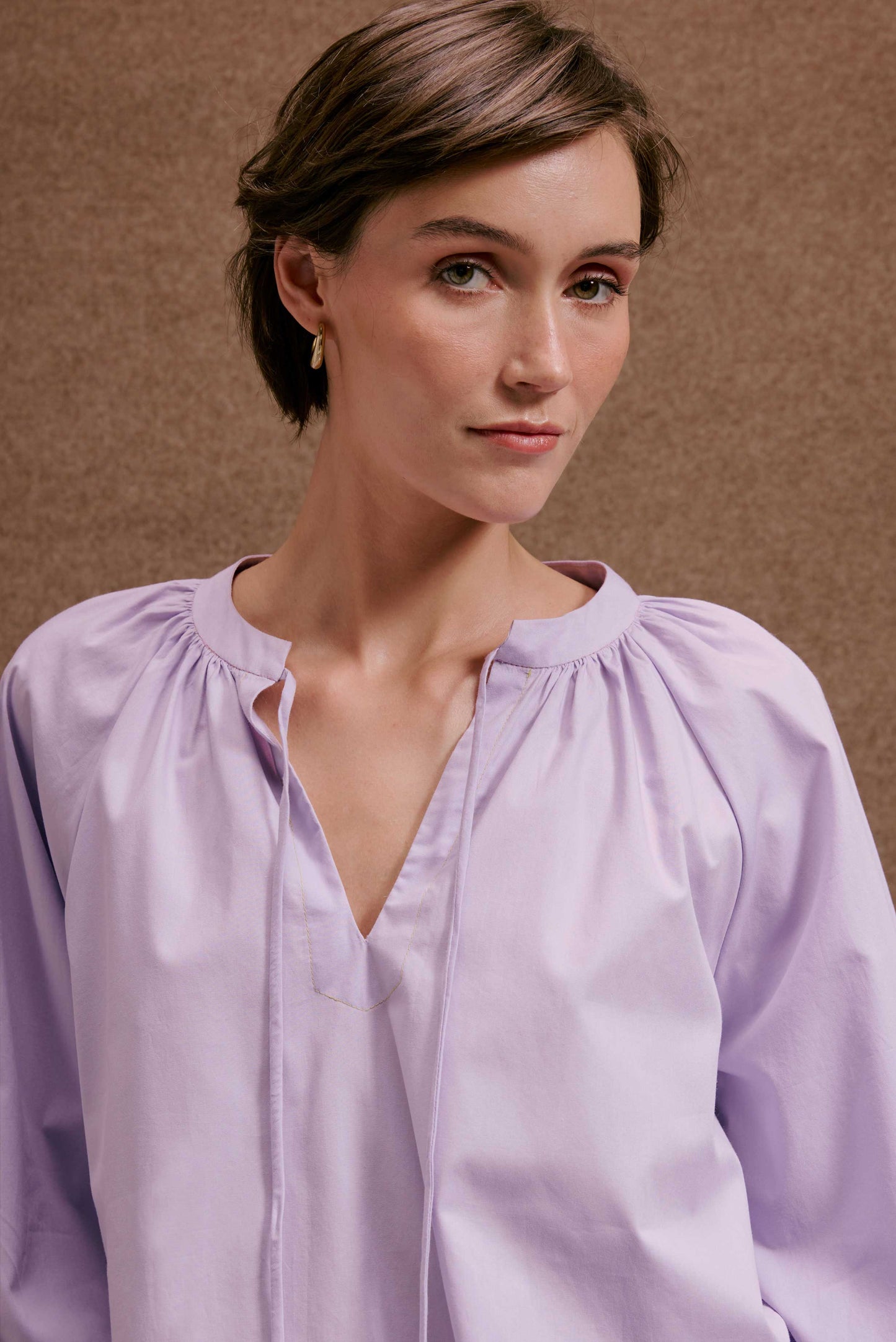 Blusa Boho Orquidário lilás em tecido leve, decote V com amarração e mangas longas franzidas.