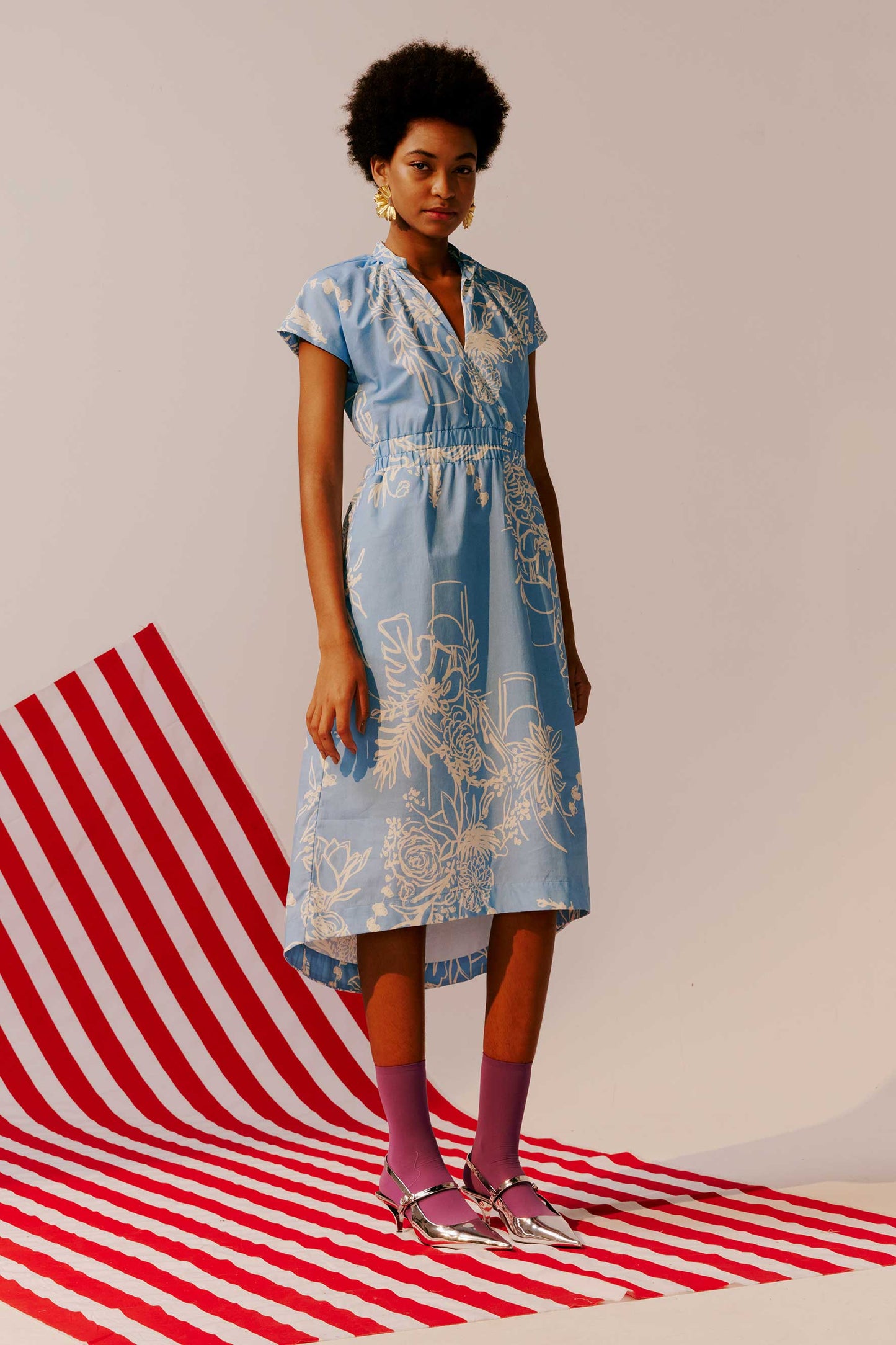 Vestido Vic Barraca das flores azul claro, estampa floral branca, manga curta, decote V, cintura elástica e barra mullet.