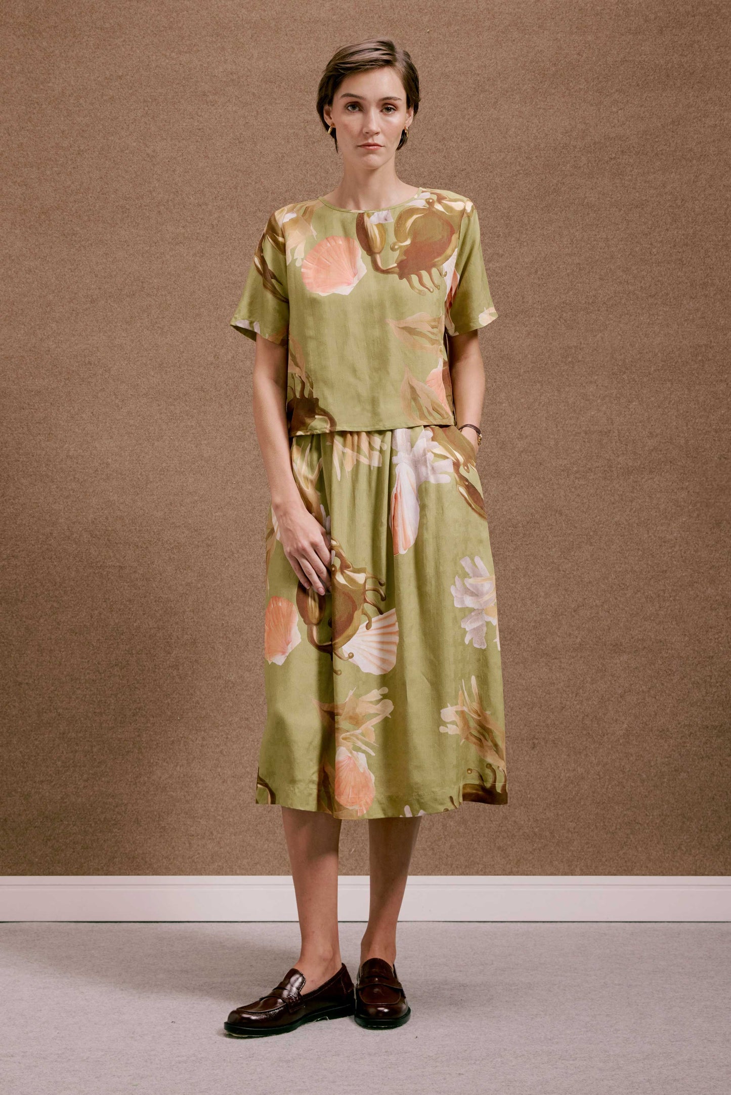 Blusa Nápoles Lembranças Verde e saia midi, conjunto com estampa de conchas e flores em coral e marrom.