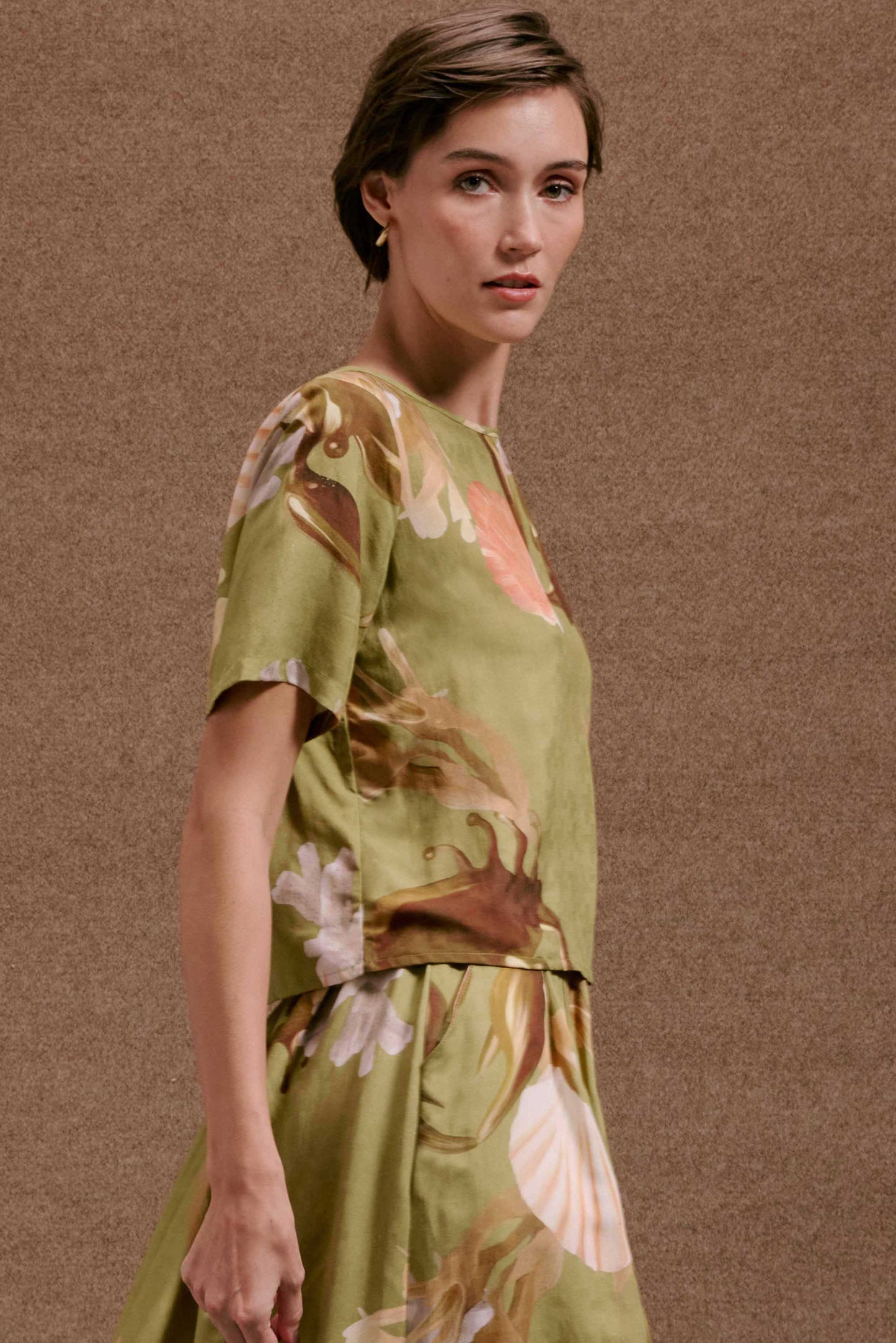 Blusa feminina Nápoles Lembranças Verde, manga curta, estampa botânica em tons terrosos e pastel.