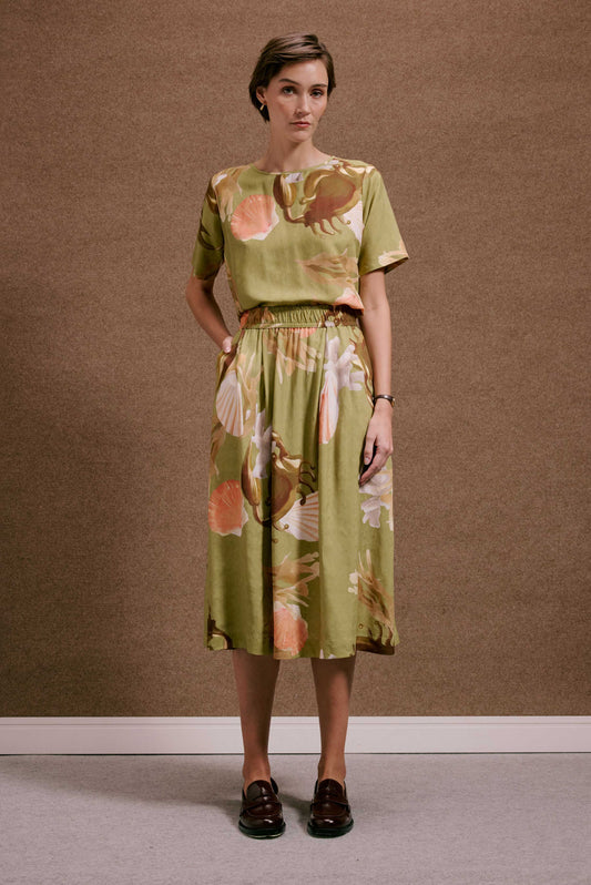 Saia rodada Lembranças Verde, estampa de conchas e folhagens em look completo verde oliva, com top e tecido leve.