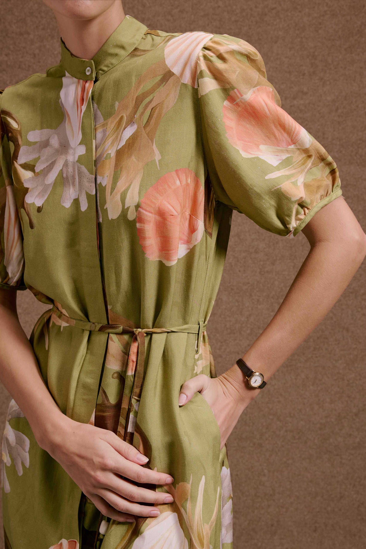 Vestido Roma Lembranças Verde, chemise floral em tons terrosos, mangas bufantes, cinto e mão no bolso. Textura natural.