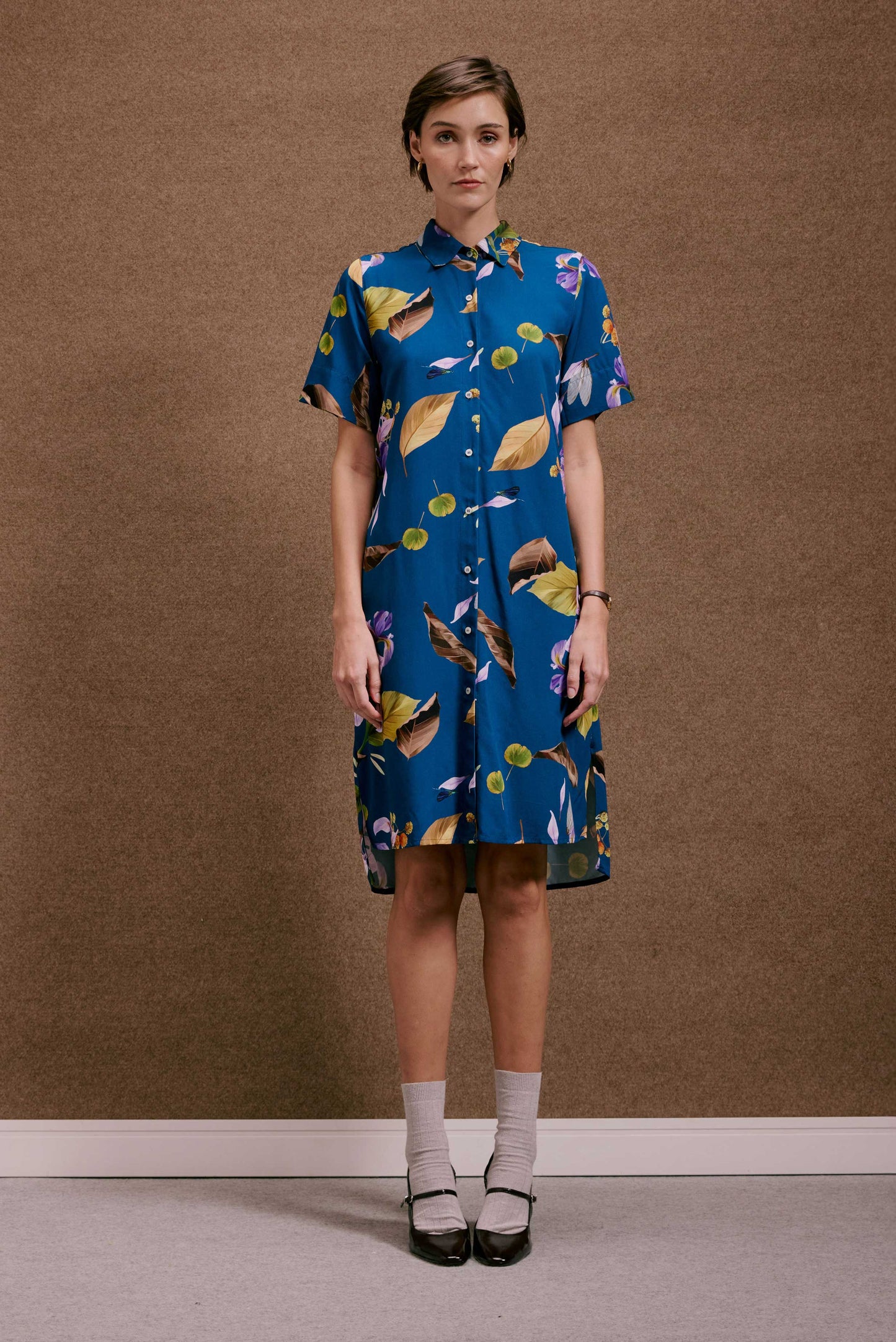 Chemise Fenda Anoitecer Botânica azul, estampa de folhas e flores, mangas curtas, botões frontais.