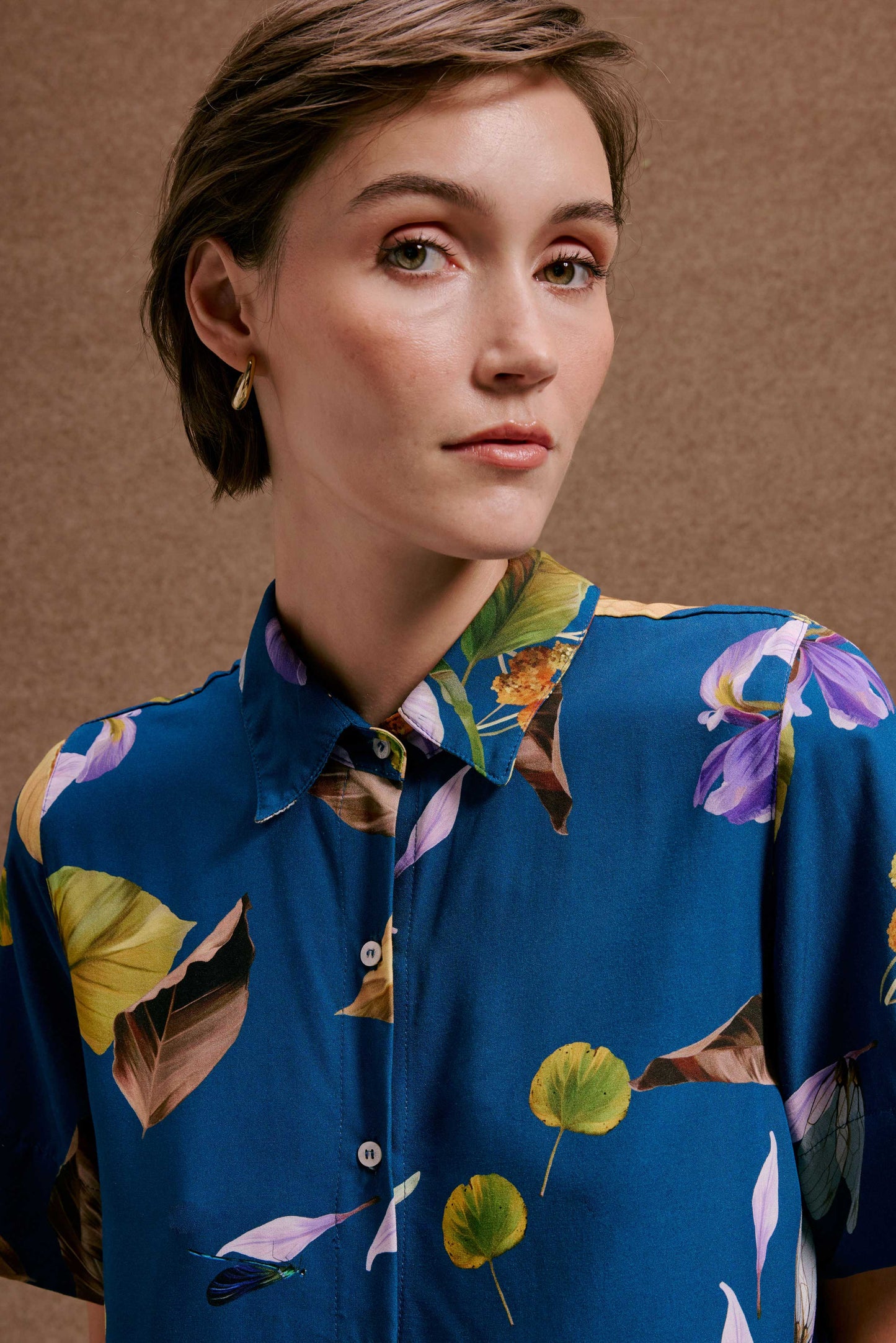 Chemise Anoitecer Botânica, azul intensa com estampa de folhas verdes, marrons e flores lilás. Caimento fluido.