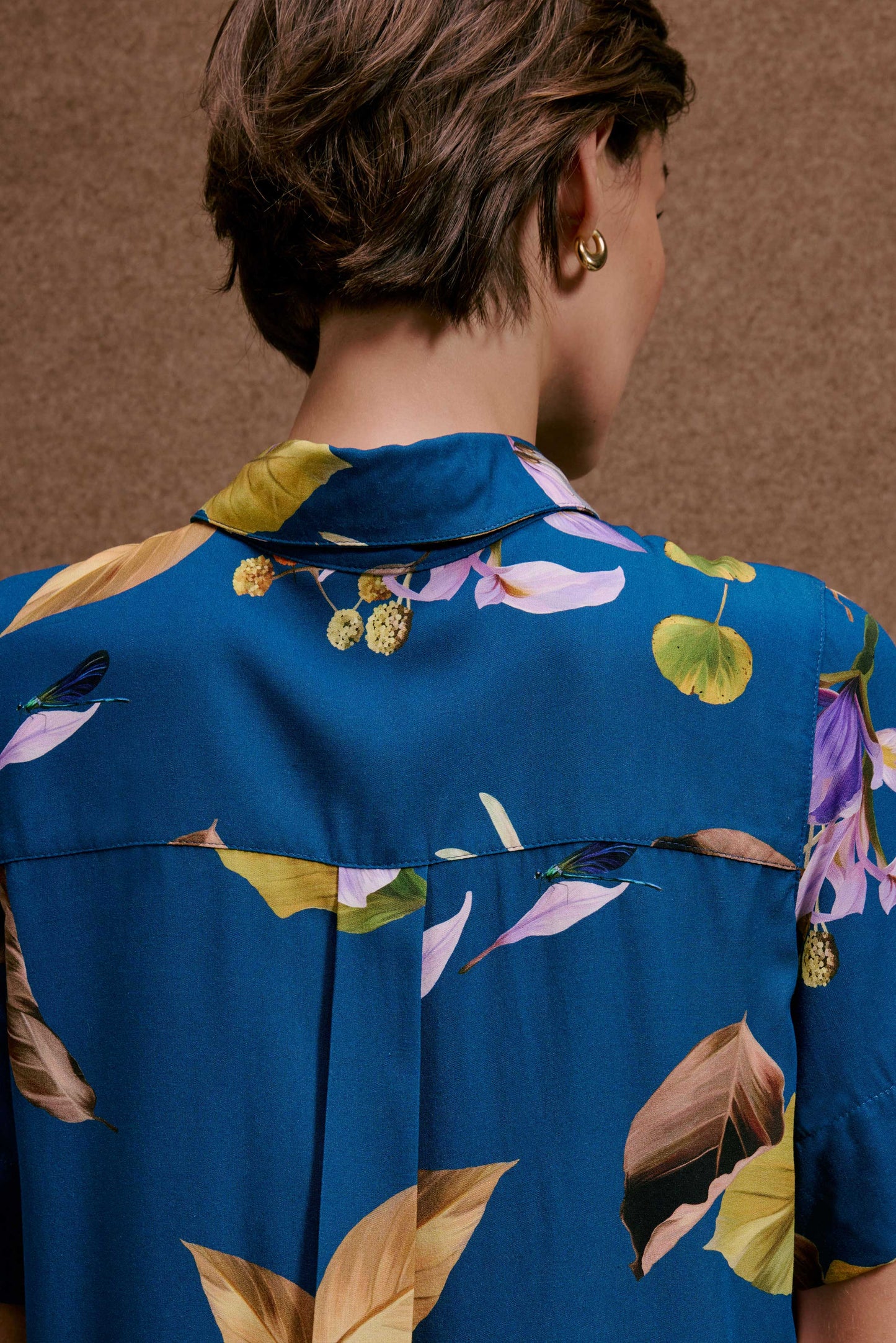 Chemise Fenda Anoitecer Botânica azul com estampa botânica de folhas, flores roxas e libélulas. Tecido fluido.