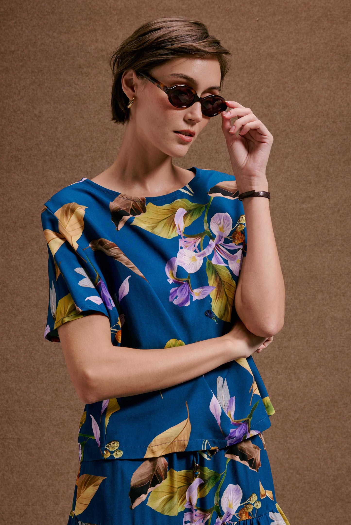 Blusa Japa New azul vibrante com estampa Anoitecer Botânica: folhas marrons e flores roxas. Elegante e solta.