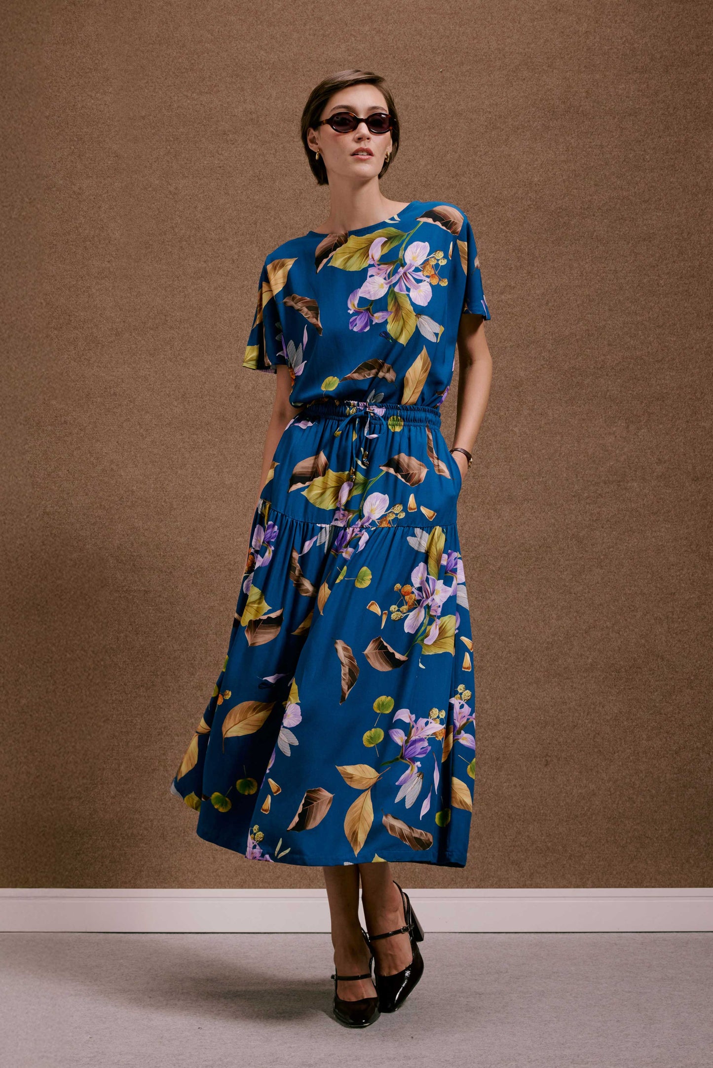 Vestido azul midi com estampa botânica 'Saia Gipsy Anoitecer Botânica'. Modelo fluido de mangas curtas e cintura elástica.