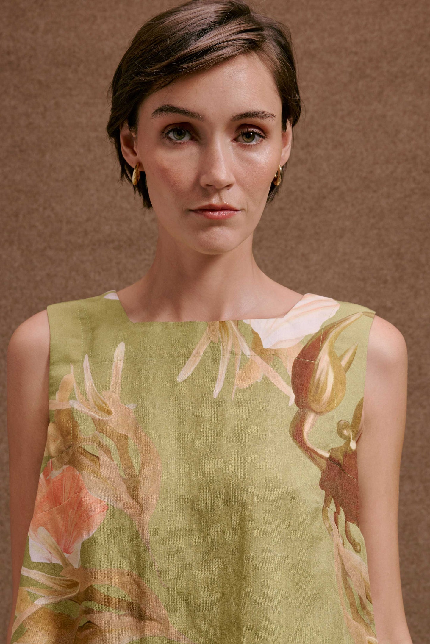 Blusa Quadradinha Lembranças Verde floral em tons de verde, laranja e marrom, tecido leve, sem mangas.