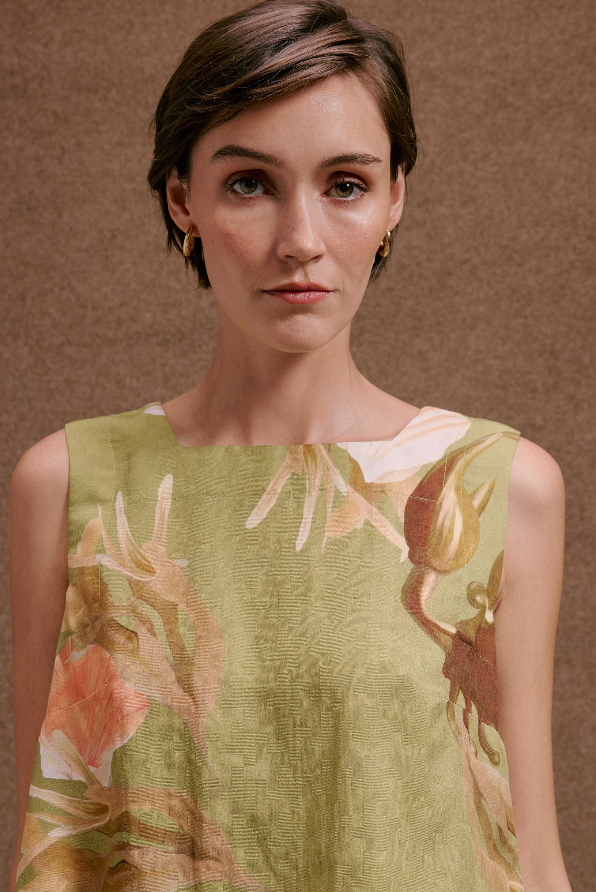 Blusa Quadradinha Lembranças Verde floral em tons de verde, laranja e marrom, tecido leve, sem mangas.