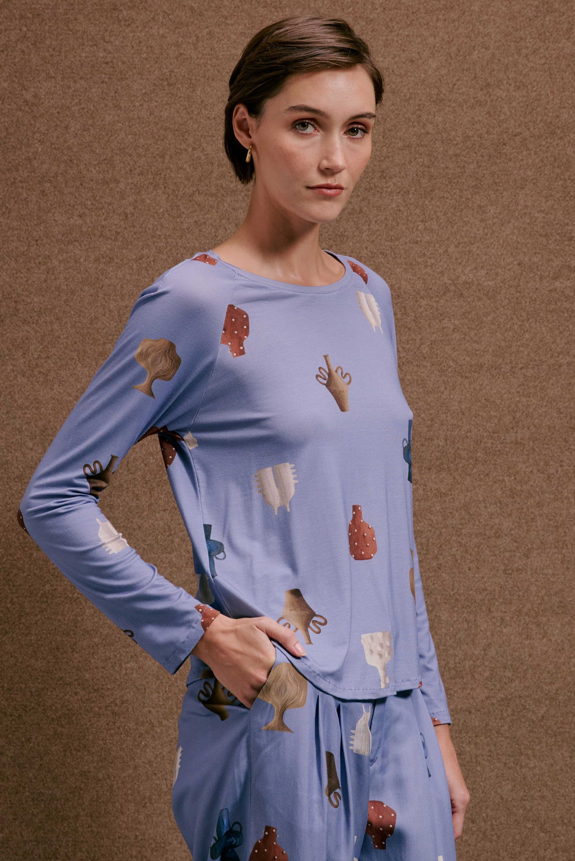 Blusa Raglan Vasinhos Mini de manga longa azul-claro, com estampa de vasos e formas abstratas em tons terrosos.