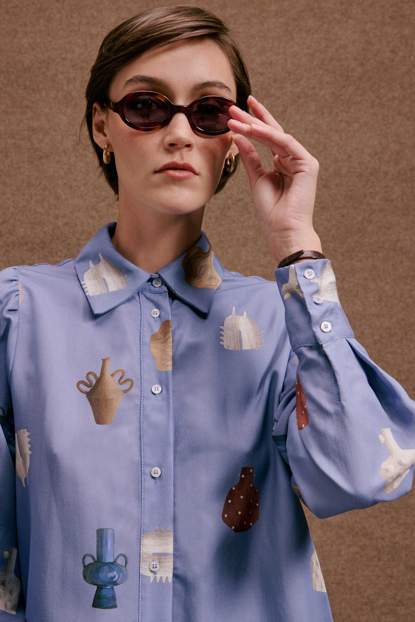 Camisa Studio Vasinhos Mini azul claro, estampa de vasos em tons neutros e terrosos, mangas bufantes, estilo casual chic.