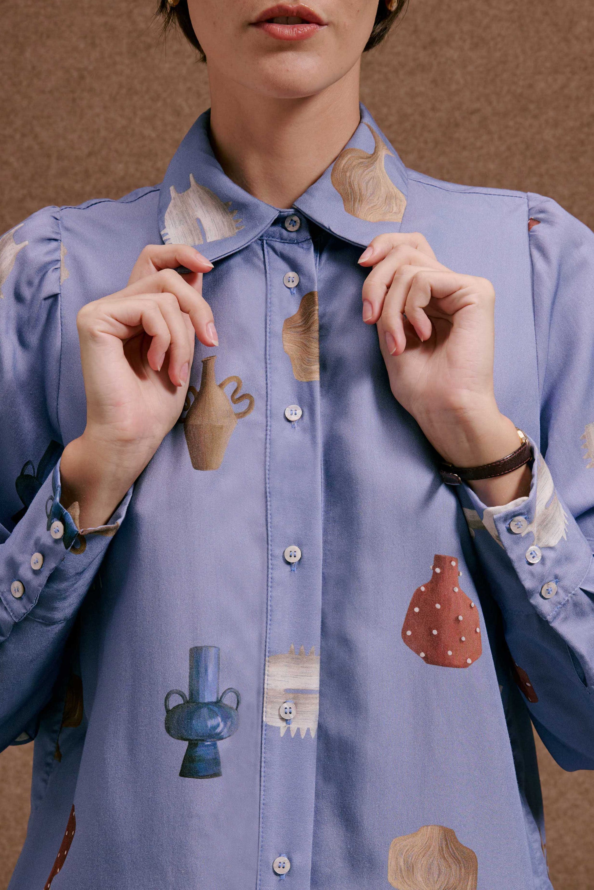 Camisa Studio Vasinhos Mini azul arroxeado, estampa de vasos terrosos e azuis, tecido com leve textura.