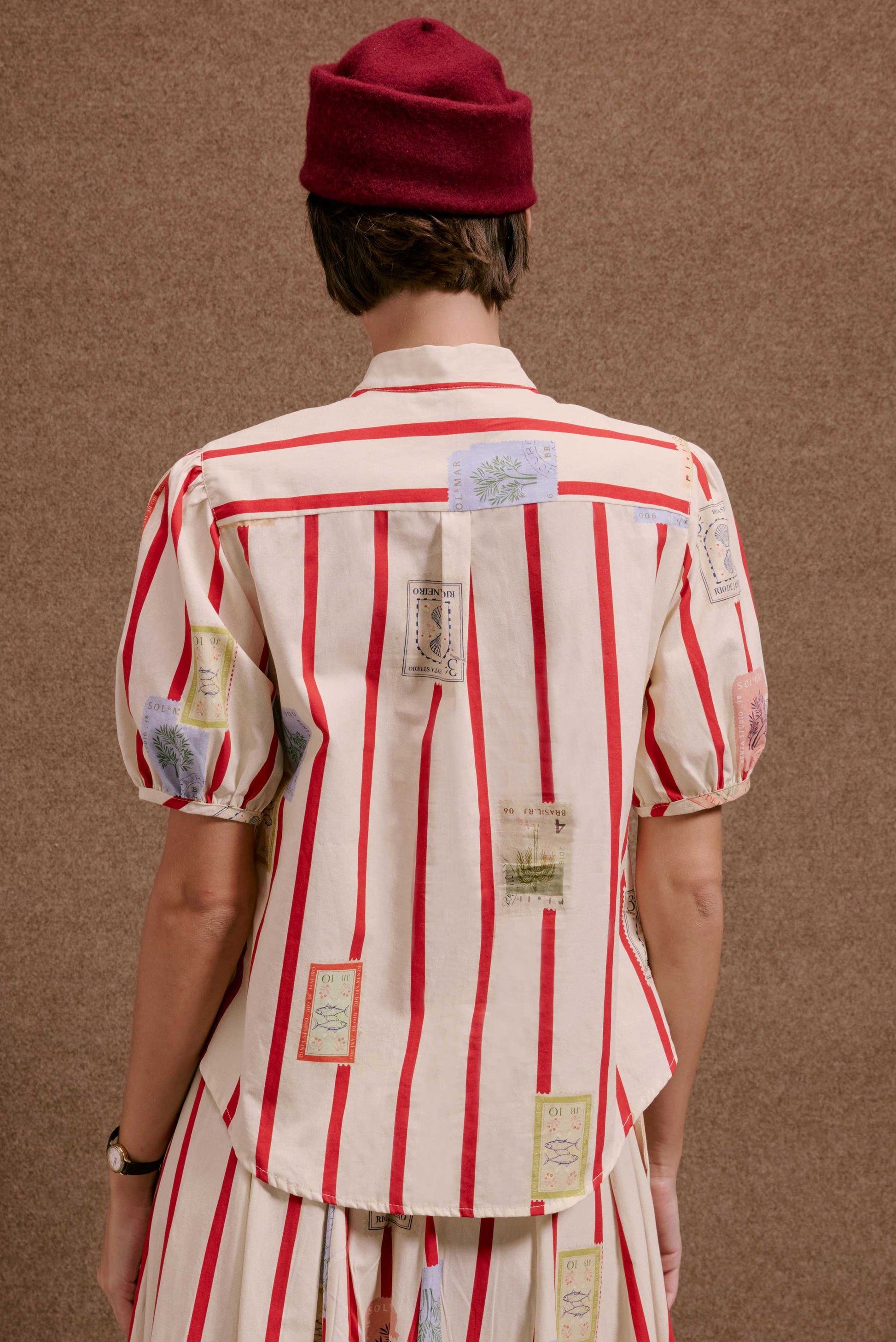 Blusa Roma Selos Listras. Creme com listras vermelhas e aplicações de selos com plantas, conchas e peixes. Manga bufante.