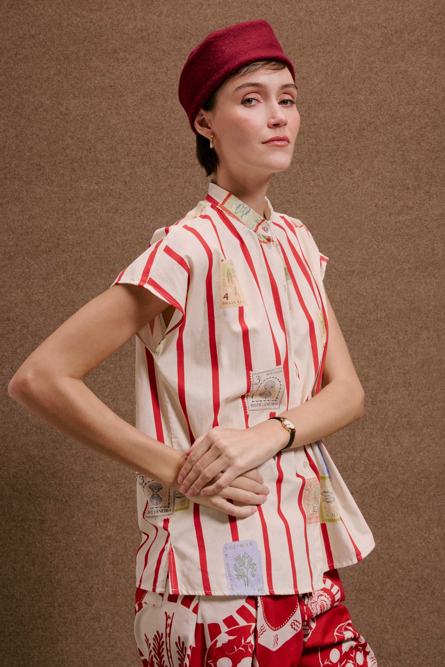 Camisa Gênova Selos Listras, blusa feminina de algodão branca com listras vermelhas verticais e selos estampados.