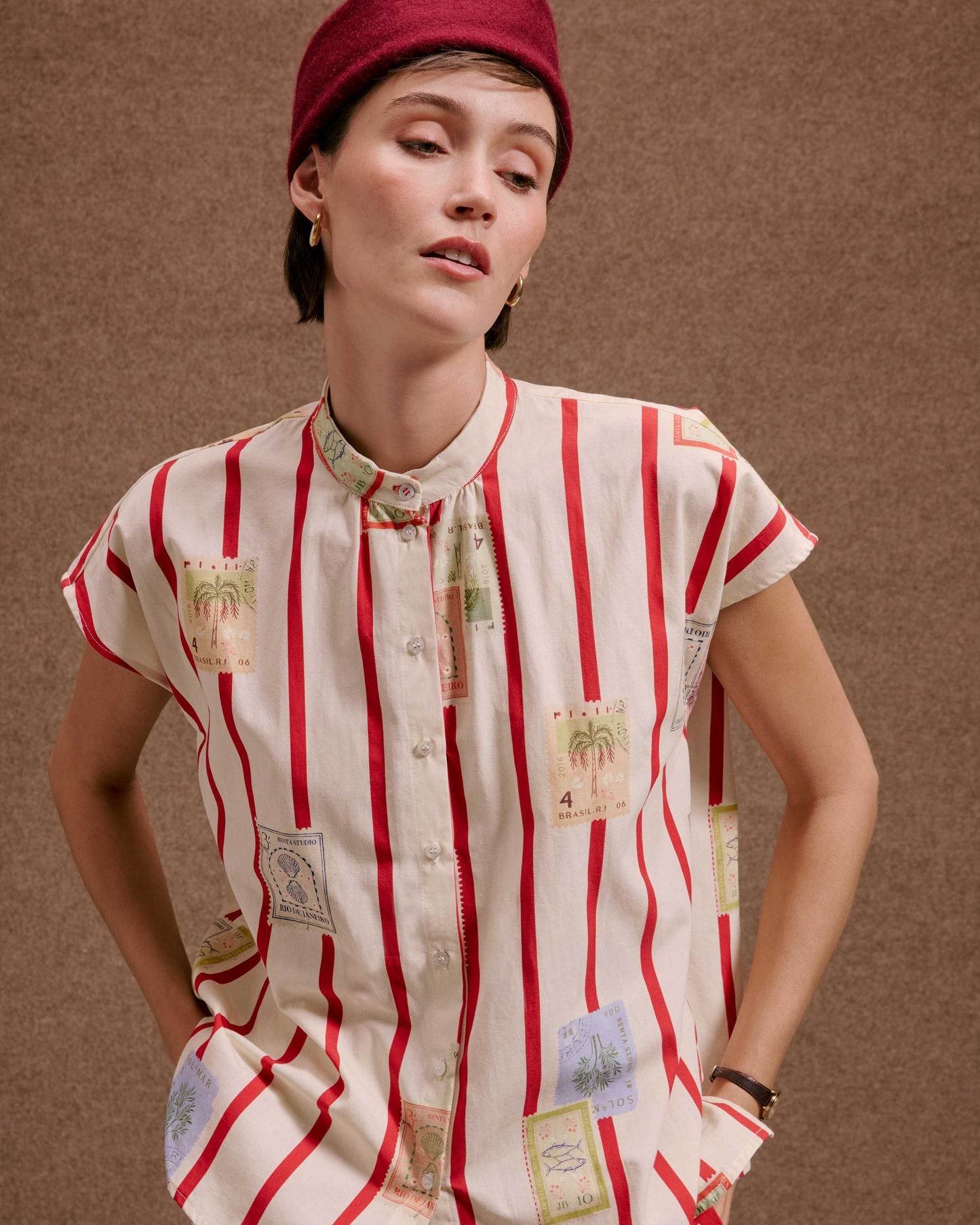 Camisa Gênova Selos Listras: feminina, creme com listras vermelhas e estampas de selos postais, gola padre.
