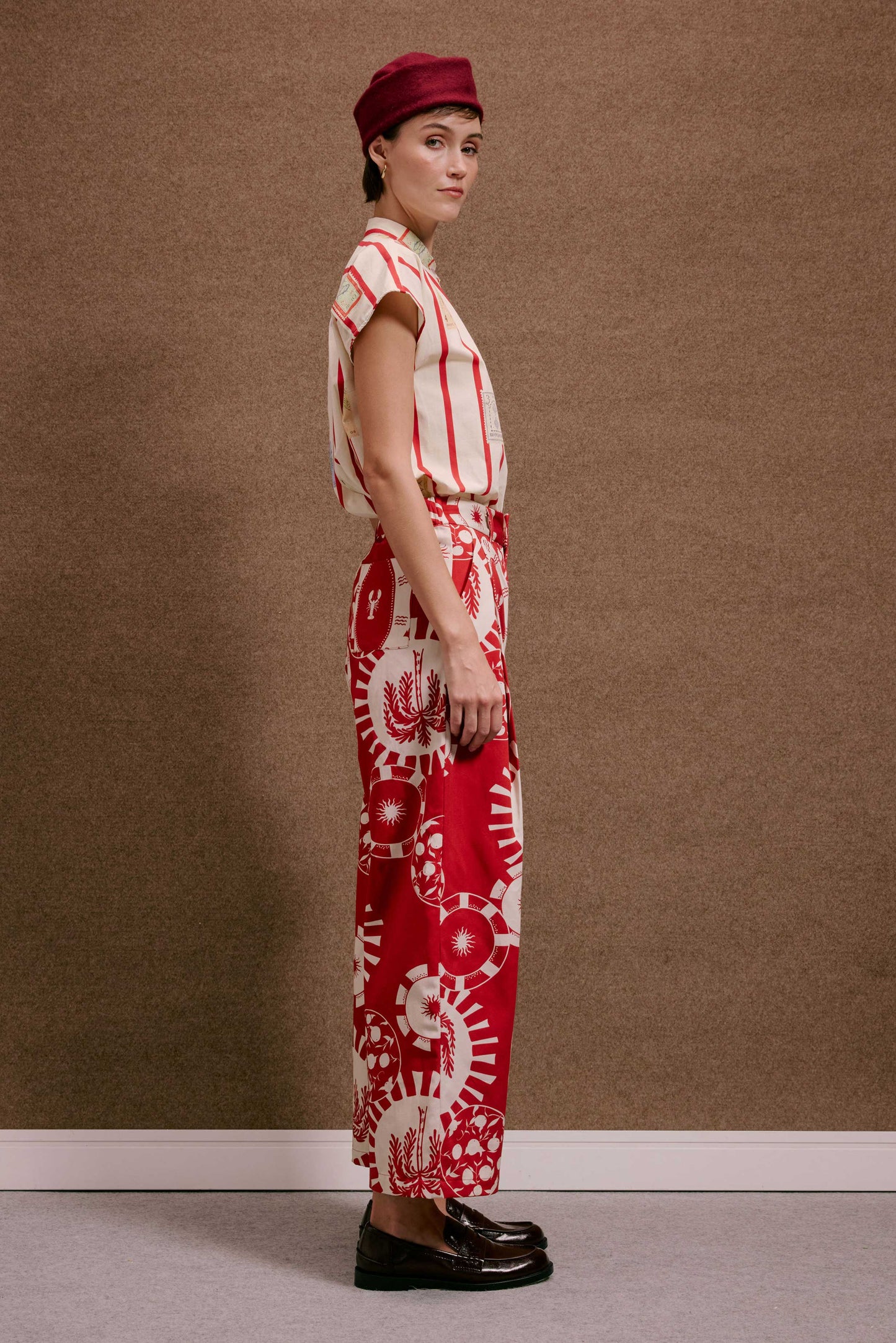 Calça Japão Pratinhos Vermelho, com estampa detalhada branca de círculos e sol, vestida por modelo em perfil.