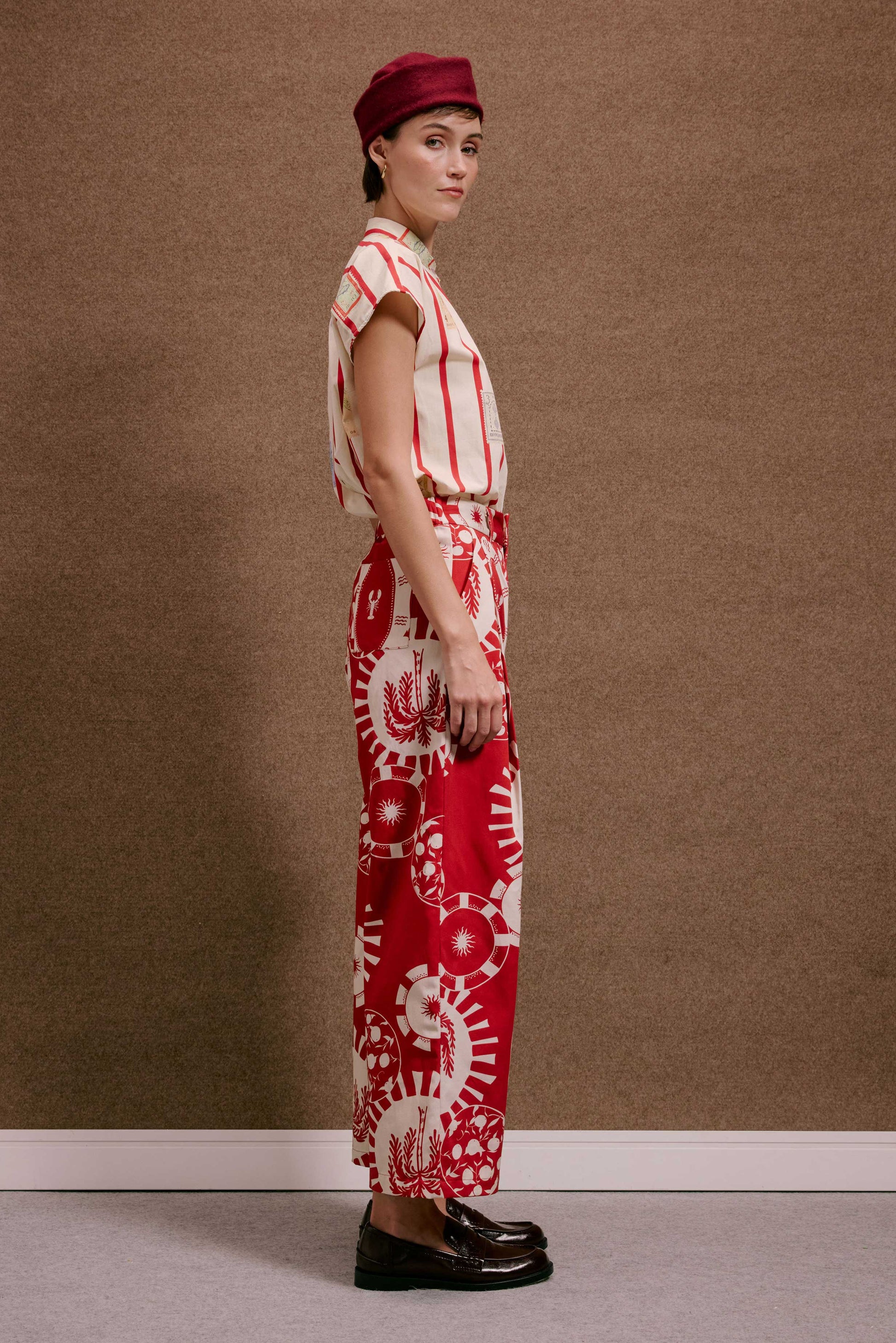 Calça Japão Pratinhos Vermelho, com estampa detalhada branca de círculos e sol, vestida por modelo em perfil.