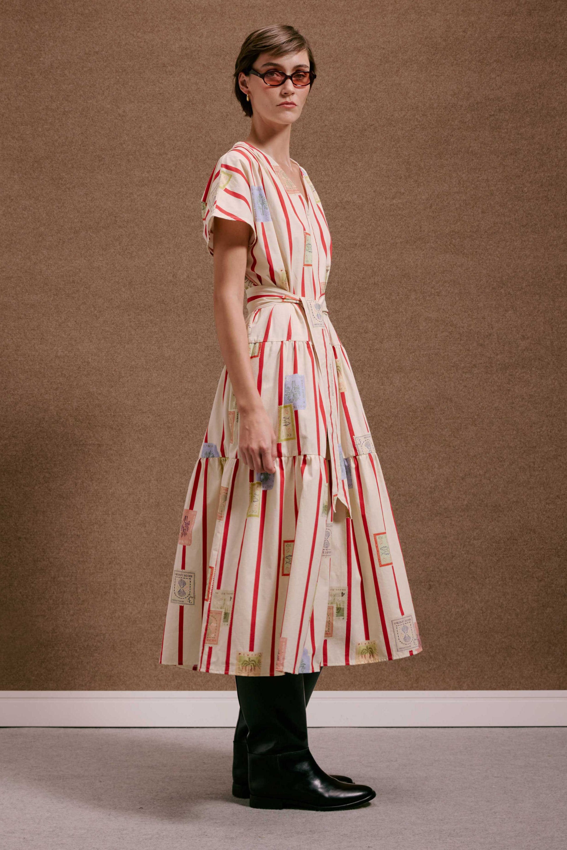 Vestido Galeria Selos Listras: midi creme com listras vermelhas, estampa de selos. Decote V, cinto, saia em camadas.