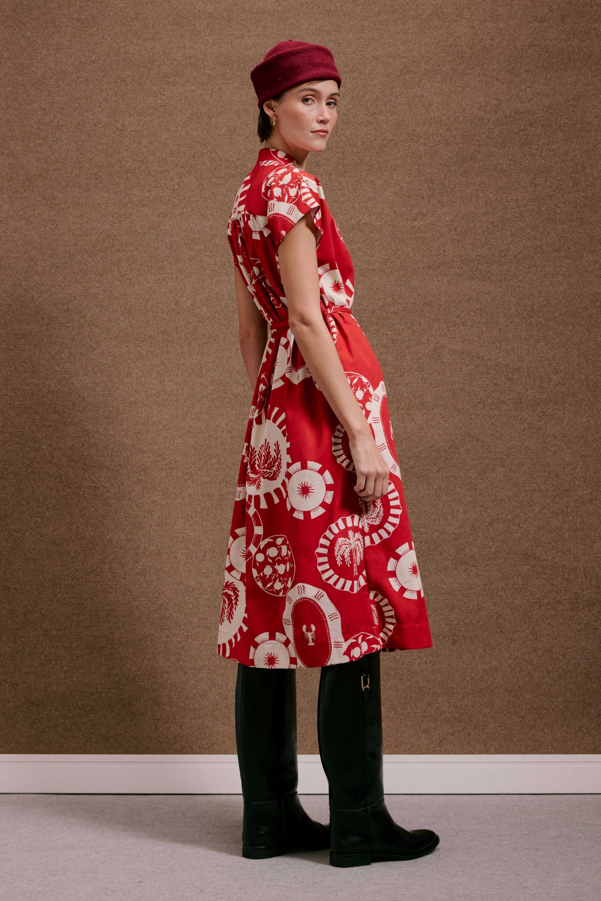 Vestido Gênova Pratinhos Vermelho midi, tecido leve, com estampa de sol, coqueiro e lagosta. Cintura marcada, manga curta.