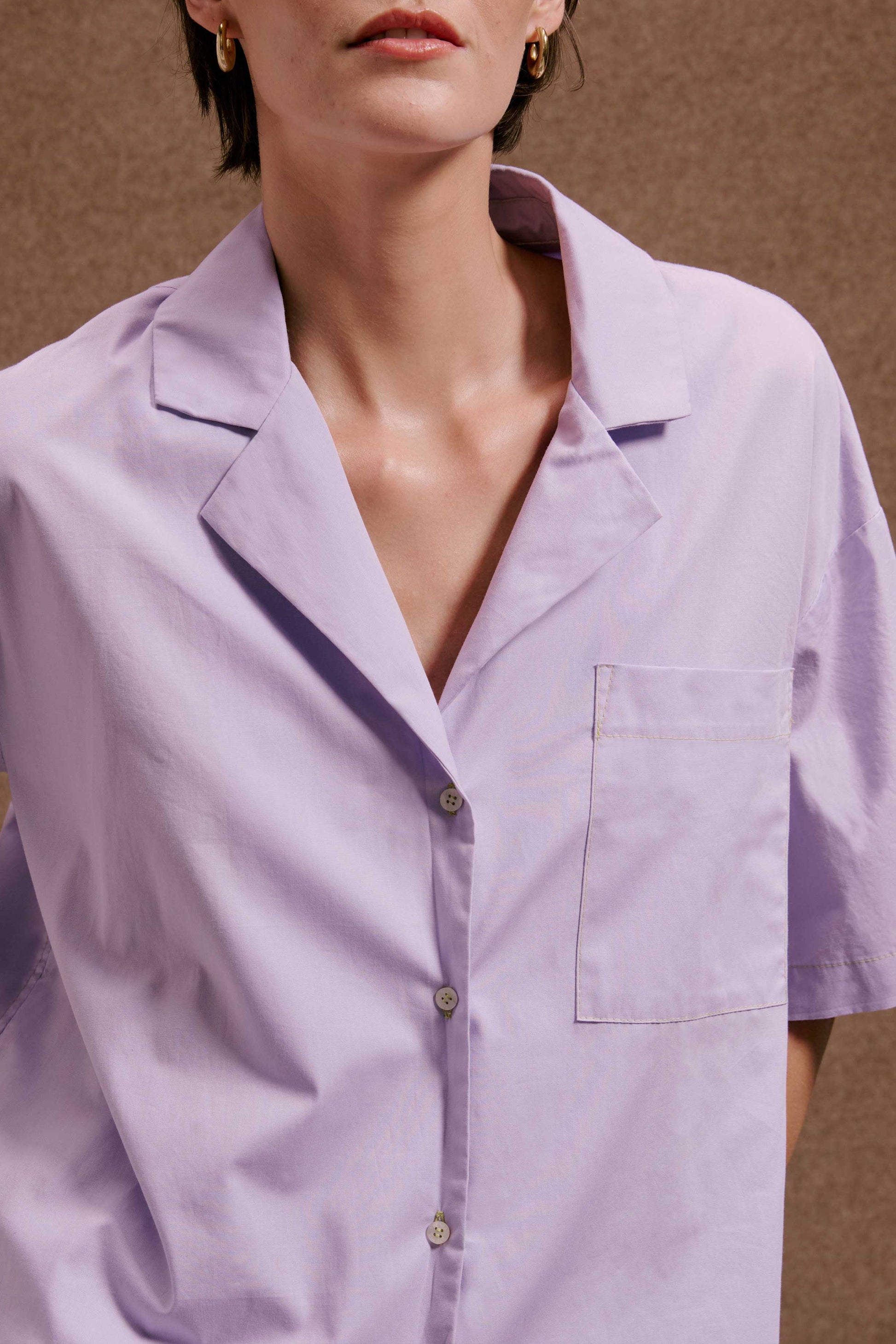 Camisa Havana Orquidário em algodão lilás, com gola aberta, botões claros e bolso.